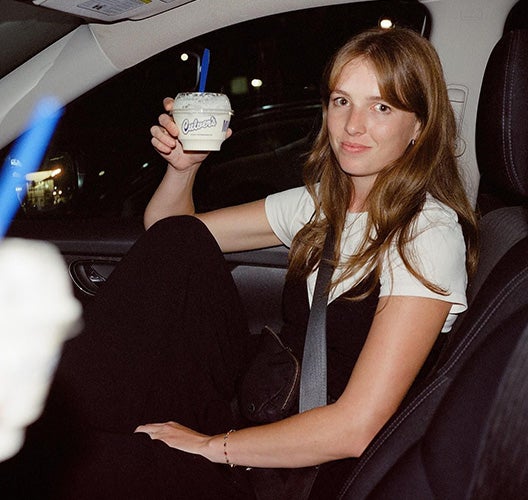 Woman holding Fresh Frozen Custard dish in a car