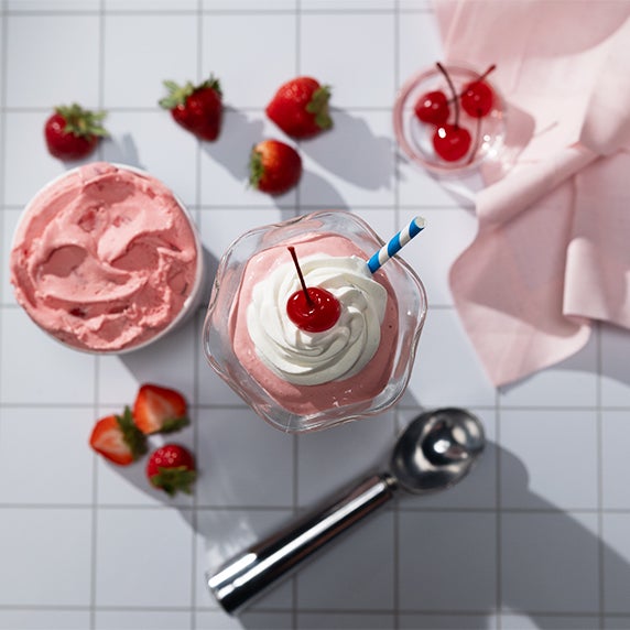 Frozen custard supper club Pink Squirrel mocktail drink with whipped cream and a cherry on top in a glass.