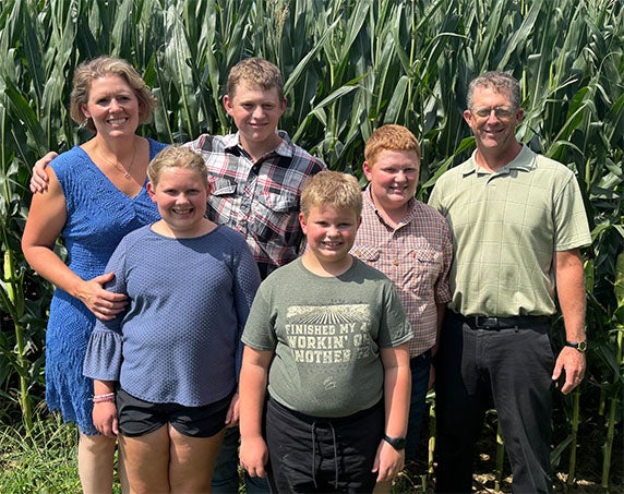 Family standing in front of corn stalks.