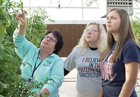 Link to story: Waupun FFA: Growing Tomorrow's Leaders. Waupun FFA advisor and members stand in a greenhouse inspecting tomato plants
