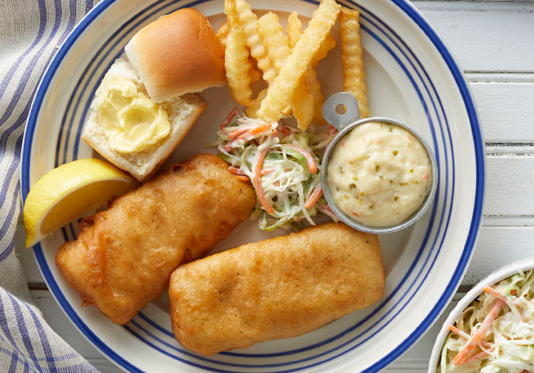 Link to story: Fish Fries: Five Midwestern Meal Must Haves. A Midwestern fish fry including, Cod, buttered dinner roll, crinkle cut fries, tartar sauce and coleslaw.
