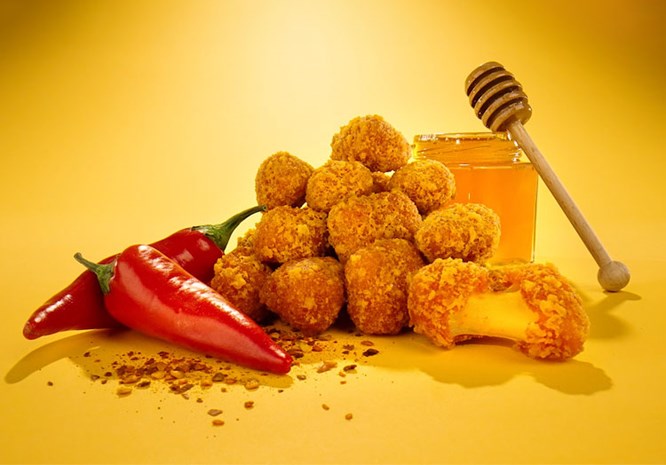 Hot Honey Curds sit in between hot peppers and a jar of honey.