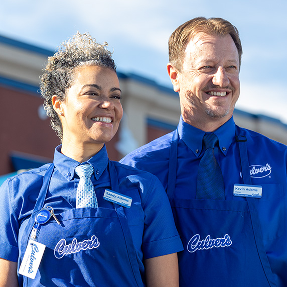 A smiling Kevin and Sandy Adams stand in front of a Culver’s restaurant. 