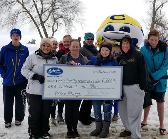 Team members stand in a group holding a check.