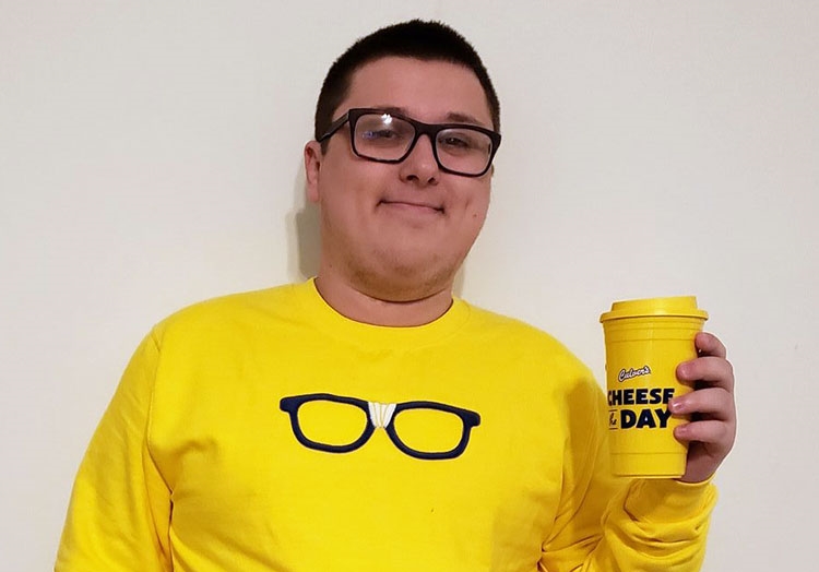 Link to story: Culver's Guest has same name as restaurant. Kurtis Culver wearing a yellow Curd Nerd sweatshirt with black framed glasses, and holding a “Cheese the Day” yellow travel mug. 