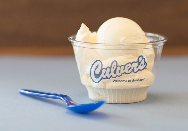 Link to story: 5 Reasons to Celebrate Scoops of Thanks Day. Single Scoop Dish of Vanilla on a table with a blue spoon