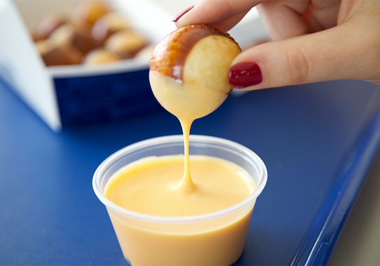 Link to story: So Dippable: Wisconsin Cheddar Cheese Sauce. Pictured, Pretzel Bite dipping into Cheese Sauce.
