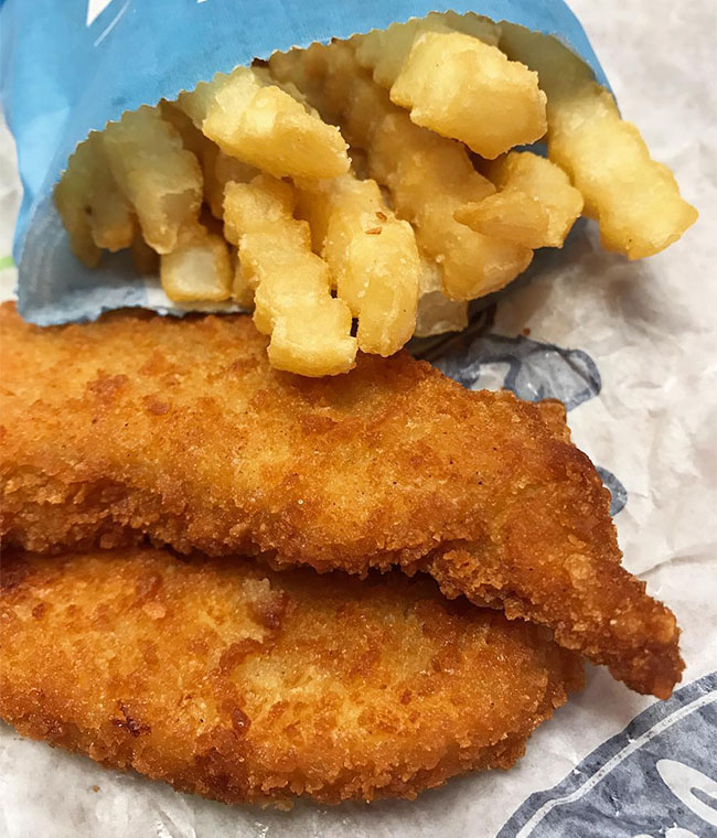 Two Culver’s Chicken Tenders lay next to a bag of Crinkle Cut Fries.