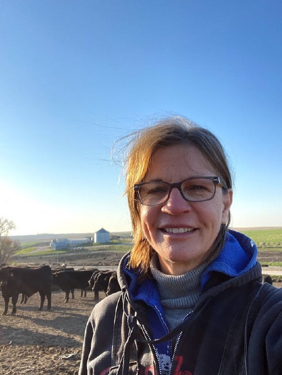 Joan Ruskamp stands in front of cattle